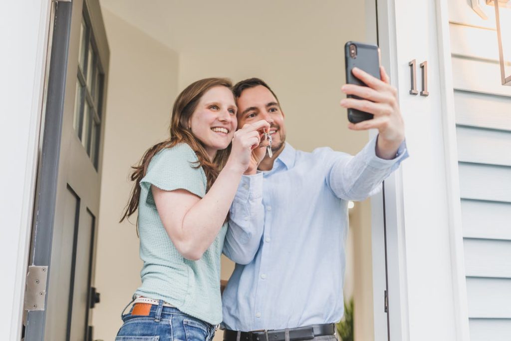 couple buying a home taking photo with keys